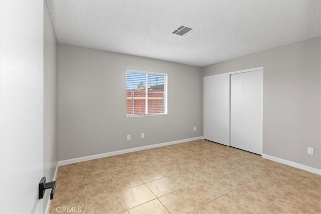 unfurnished bedroom with baseboards, visible vents, a closet, and a textured ceiling