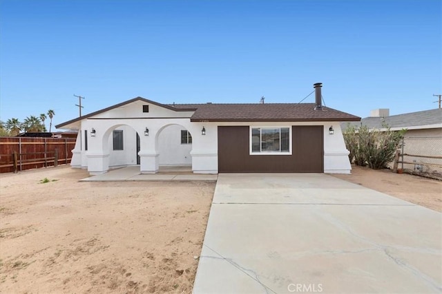 view of front of house with stucco siding, a patio area, and fence