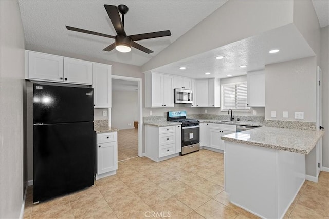 kitchen featuring a peninsula, lofted ceiling, appliances with stainless steel finishes, a textured ceiling, and white cabinetry