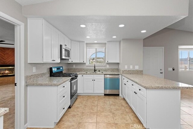 kitchen featuring light tile patterned floors, a peninsula, stainless steel appliances, and a sink