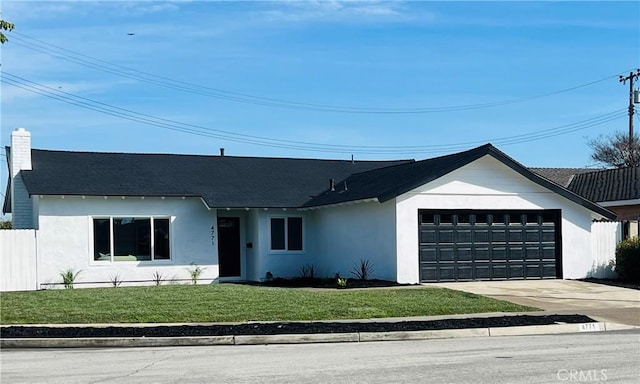 view of front of property featuring concrete driveway, an attached garage, a front lawn, and stucco siding