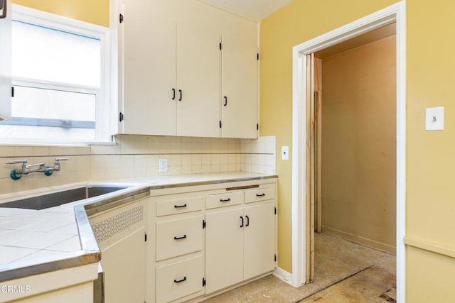kitchen featuring white cabinets, tile counters, a sink, dishwashing machine, and backsplash