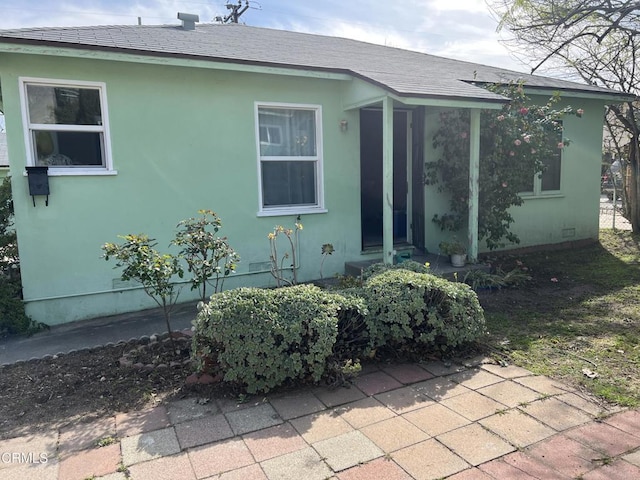 exterior space featuring stucco siding and roof with shingles