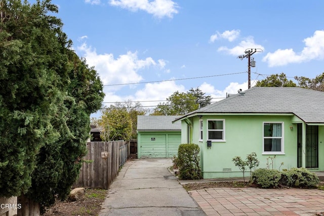 view of front of home featuring stucco siding, fence, and roof with shingles