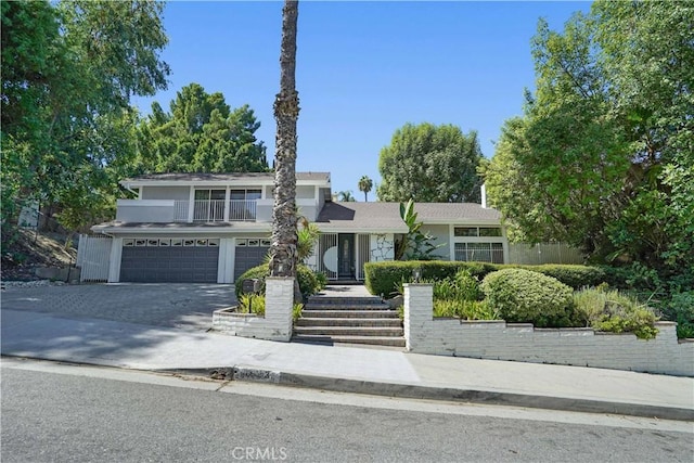 view of front of house with driveway, an attached garage, and a balcony