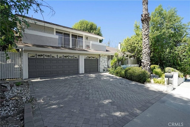 view of front facade with a balcony, decorative driveway, a garage, and stucco siding