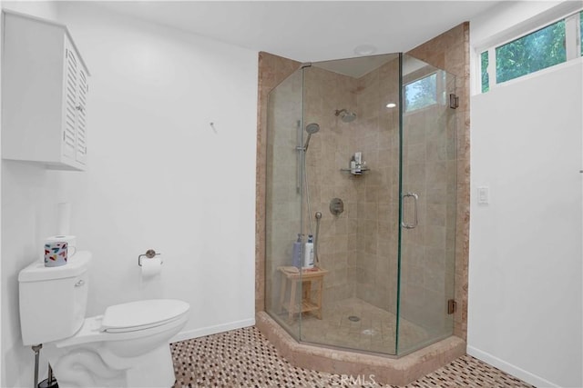 bathroom featuring tile patterned flooring, a stall shower, toilet, and baseboards