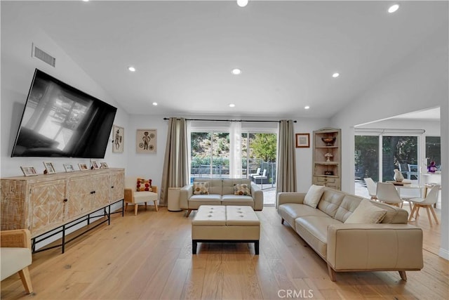 living room with vaulted ceiling, light wood-style flooring, visible vents, and baseboard heating