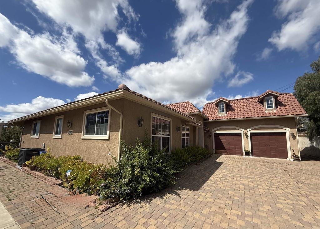 mediterranean / spanish house with a tiled roof, central AC, stucco siding, decorative driveway, and an attached garage