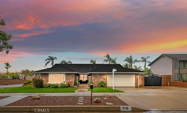 view of front of home featuring a gate, stone siding, concrete driveway, a front yard, and an attached garage