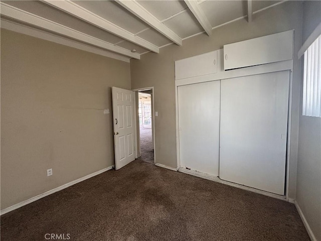 unfurnished bedroom featuring dark colored carpet, a closet, and baseboards