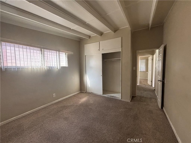 unfurnished bedroom with a closet, beamed ceiling, carpet flooring, and baseboards