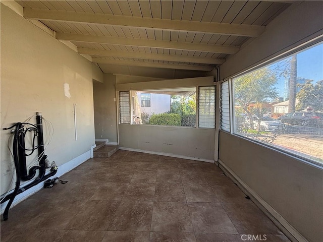 empty room featuring wood ceiling, vaulted ceiling with beams, and baseboards