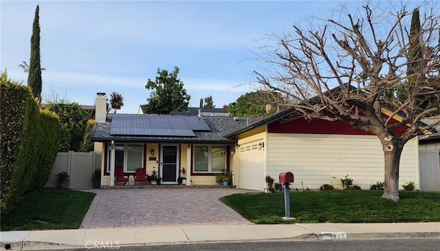 single story home with solar panels, a front lawn, fence, covered porch, and a garage