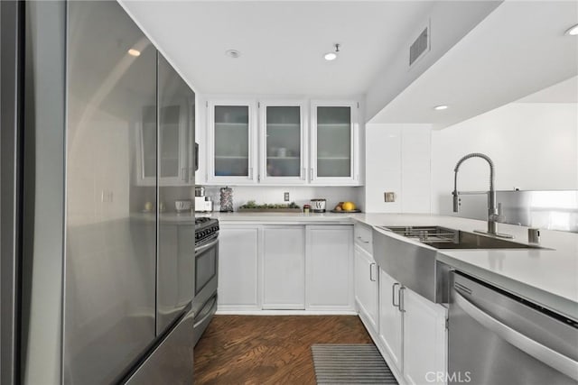 kitchen featuring visible vents, dark wood-type flooring, a sink, appliances with stainless steel finishes, and light countertops