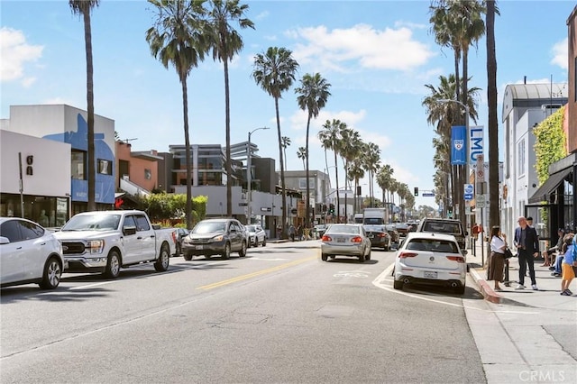 view of street featuring street lights, a residential view, curbs, sidewalks, and traffic signs