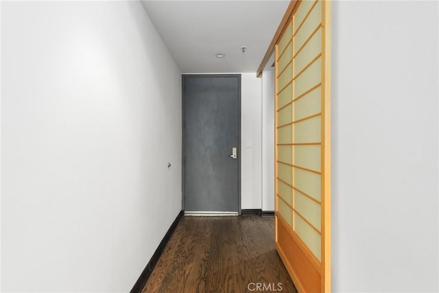 corridor featuring baseboards and dark wood-style flooring