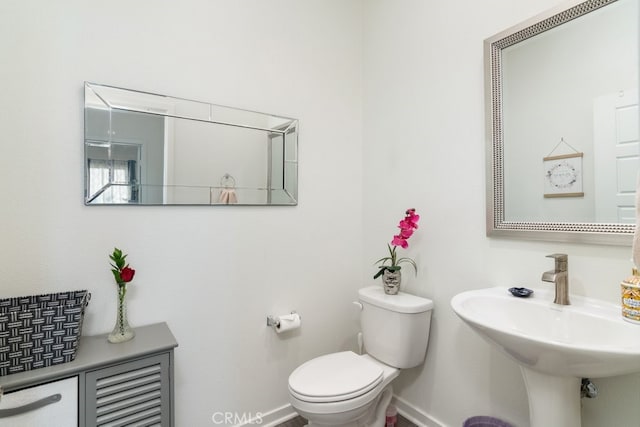 half bath with toilet, baseboards, and a sink