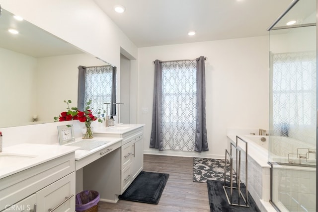 full bath featuring baseboards, recessed lighting, wood finished floors, a bath, and vanity