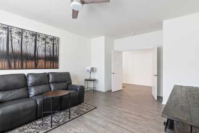 living area featuring ceiling fan, baseboards, and wood finished floors