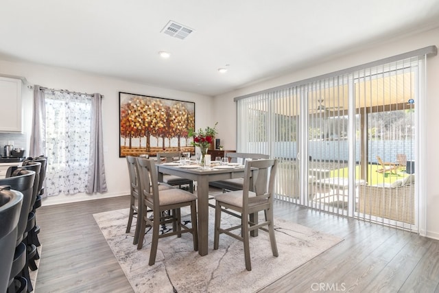 dining room featuring visible vents, baseboards, and wood finished floors