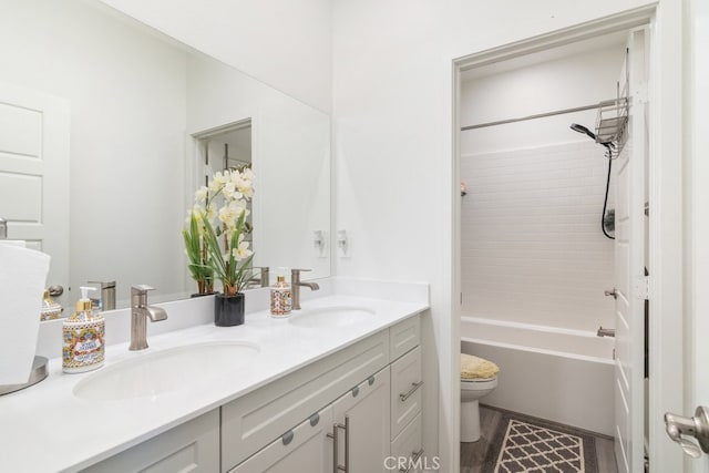 bathroom with double vanity, wood finished floors, toilet, and a sink