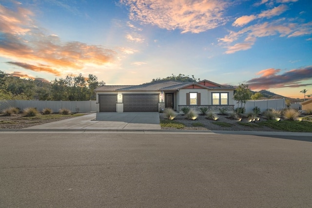 view of front of house featuring concrete driveway, an attached garage, and fence