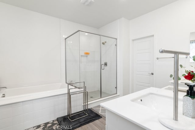 bathroom featuring wood finished floors, a stall shower, vanity, and a bath