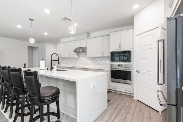 kitchen featuring visible vents, a sink, decorative backsplash, black appliances, and under cabinet range hood