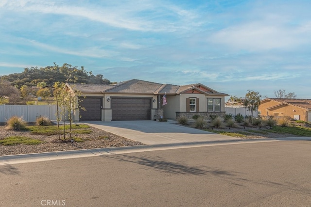 view of front of property featuring stucco siding, an attached garage, concrete driveway, and fence