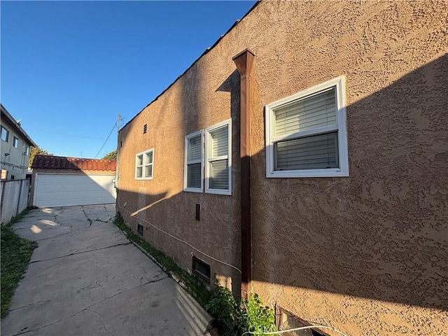 view of home's exterior with an outdoor structure, fence, and stucco siding