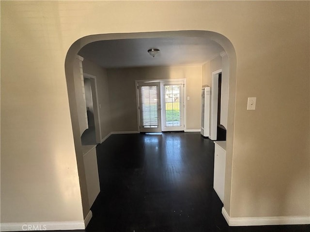 interior space with arched walkways, baseboards, and dark wood-style flooring