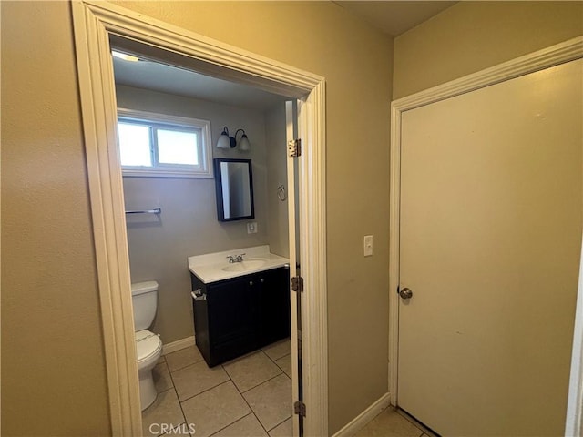 half bath featuring vanity, tile patterned floors, toilet, and baseboards