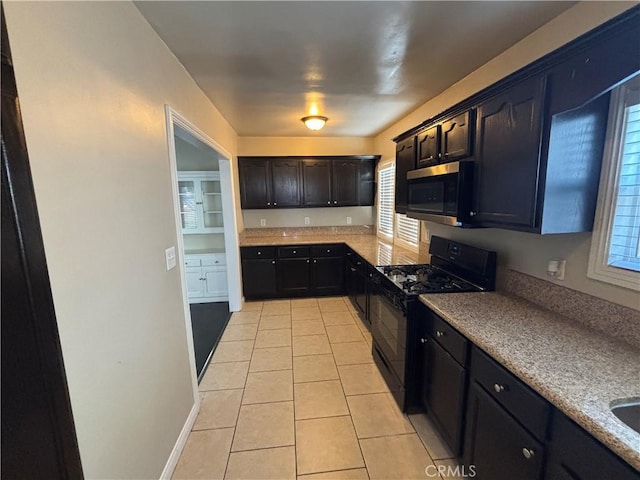 kitchen featuring stainless steel microwave, light tile patterned floors, gas stove, and plenty of natural light