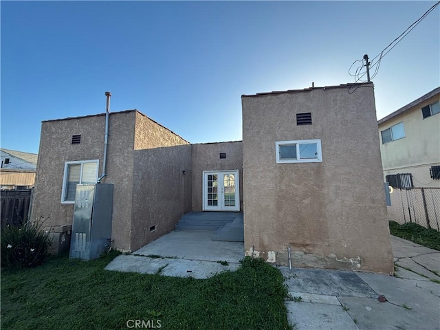 back of property with fence, stucco siding, french doors, crawl space, and a patio