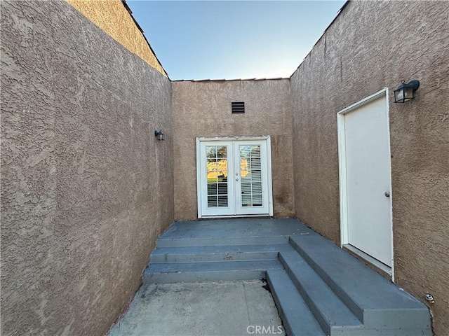 view of exterior entry with french doors and stucco siding