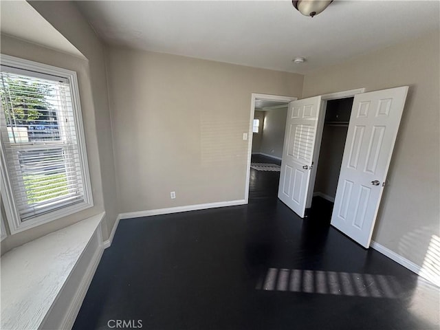 unfurnished bedroom featuring baseboards and dark wood-style flooring