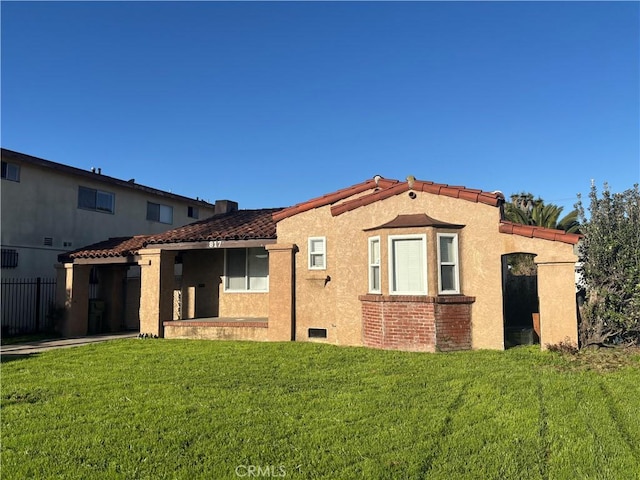 mediterranean / spanish house featuring stucco siding, a front yard, and a tiled roof