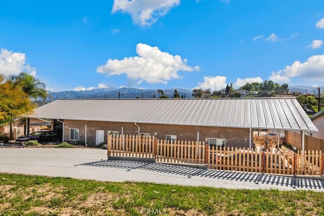 ranch-style house with a mountain view, a fenced front yard, and metal roof