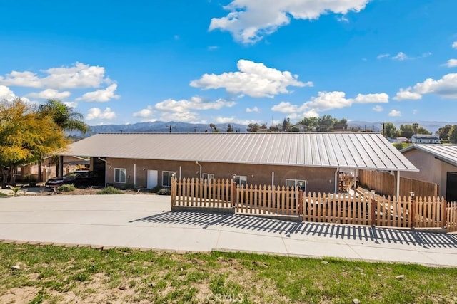 view of front of home with a standing seam roof, a fenced front yard, and metal roof