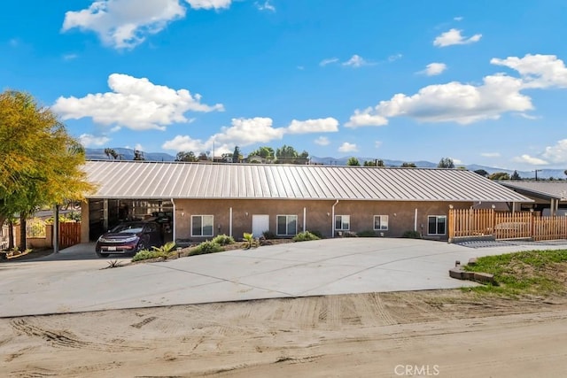 view of building exterior featuring an attached carport, driveway, and fence