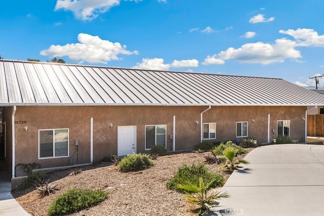 exterior space with a standing seam roof, stucco siding, and metal roof