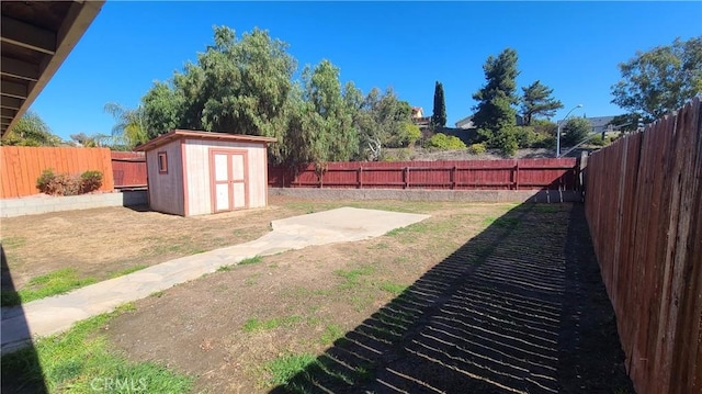 view of yard with a fenced backyard, a shed, a patio area, and an outdoor structure