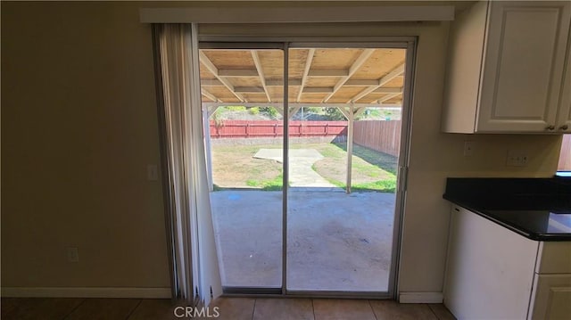 doorway to outside featuring baseboards and tile patterned flooring