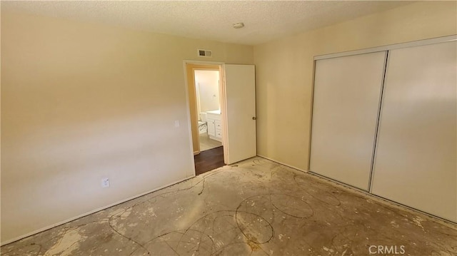 unfurnished bedroom with a closet, a textured ceiling, and visible vents