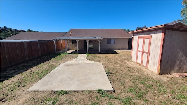 rear view of house featuring a storage shed, a fenced backyard, a yard, a patio area, and an outdoor structure