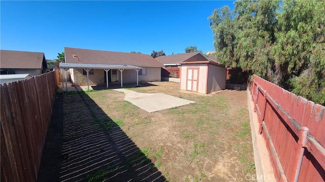 view of yard featuring a patio, a storage unit, a fenced backyard, and an outdoor structure