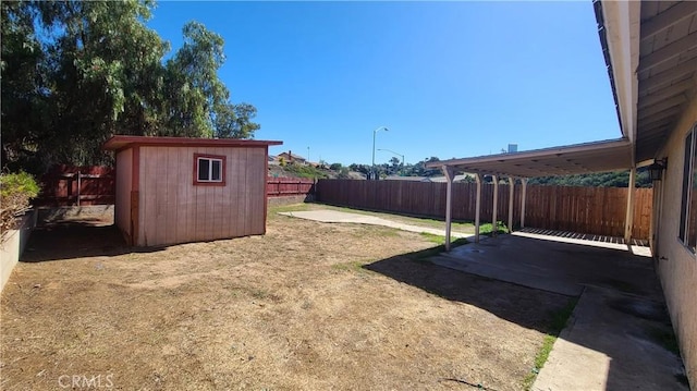 view of yard with an outbuilding, a patio area, a storage shed, and a fenced backyard