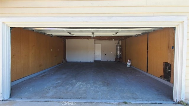 garage featuring strapped water heater and wooden walls