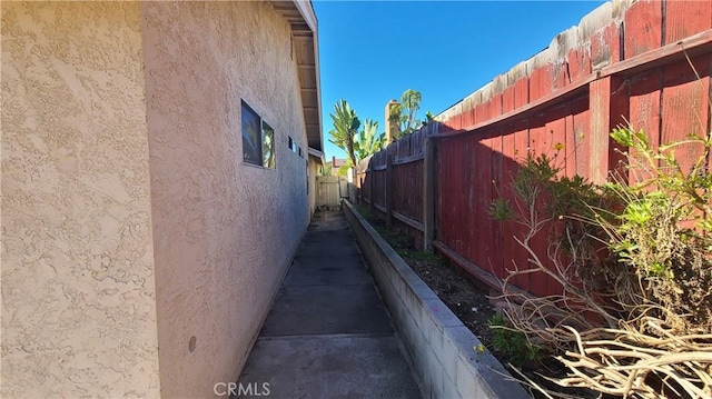 view of side of property with stucco siding and fence